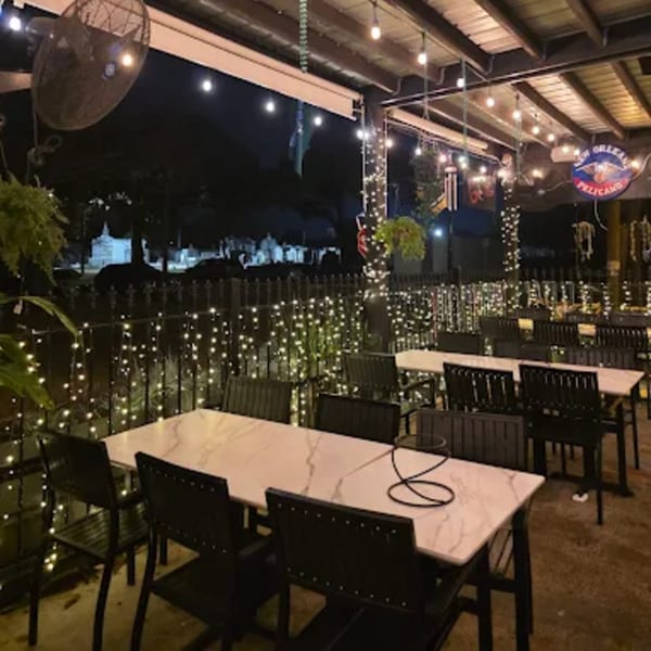 Outdoor patio dining area at night, with string lights, marble-top tables, and black chairs.